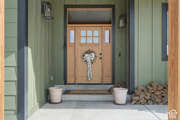 Wood-paneled entry door with sidelights, transom window, and two exterior sconce lights