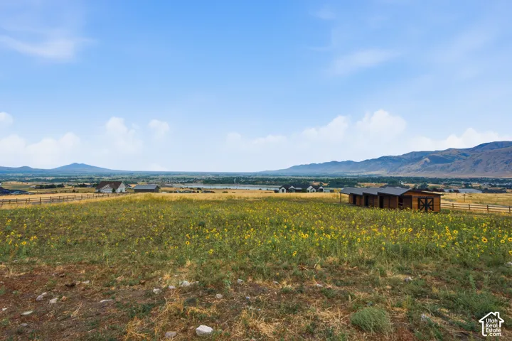 Expansive open landscape featuring a distant mountain range and multiple structures, including a white residence and several brown outbuildings