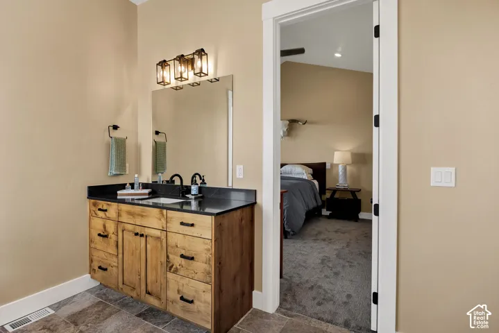 Wood-finish vanity with black countertop and integrated sink, complemented by a three-light vanity fixture