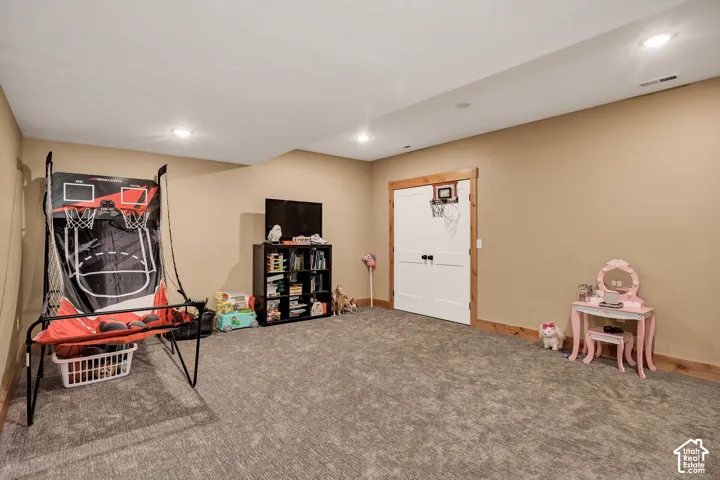 Recessed lighting illuminates a spacious room featuring wall-to-wall carpeting