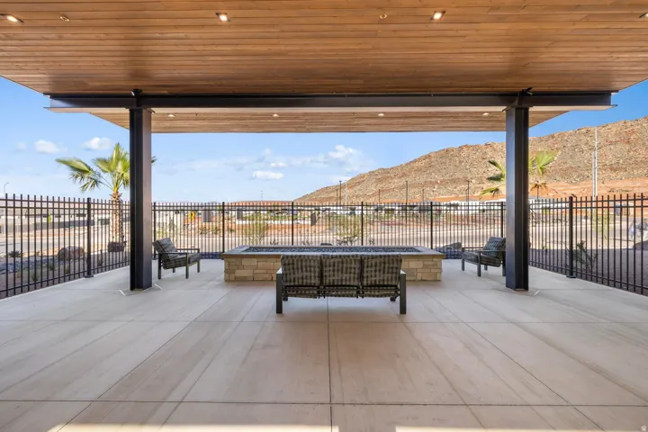 Expansive patio featuring a wood-finish ceiling with recessed lighting, concrete flooring, and a stone-clad fire pit