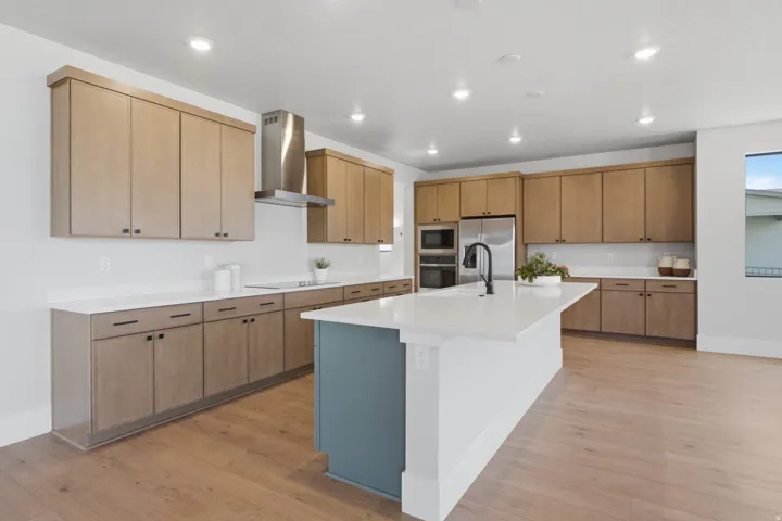 Contemporary kitchen featuring wood-finish cabinetry, white countertops, stainless steel appliances, and a central island with a contrasting base