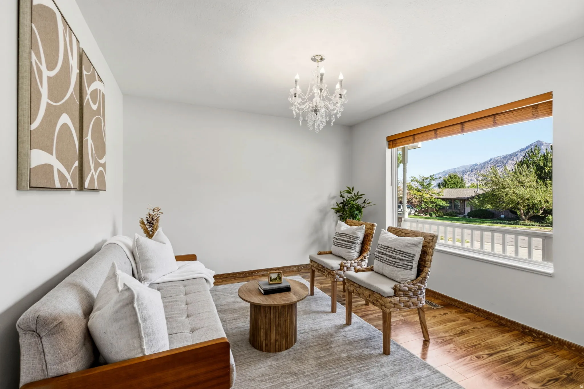 Hardwood-finish flooring, crystal chandelier, expansive window, mountain backdrop, and white walls