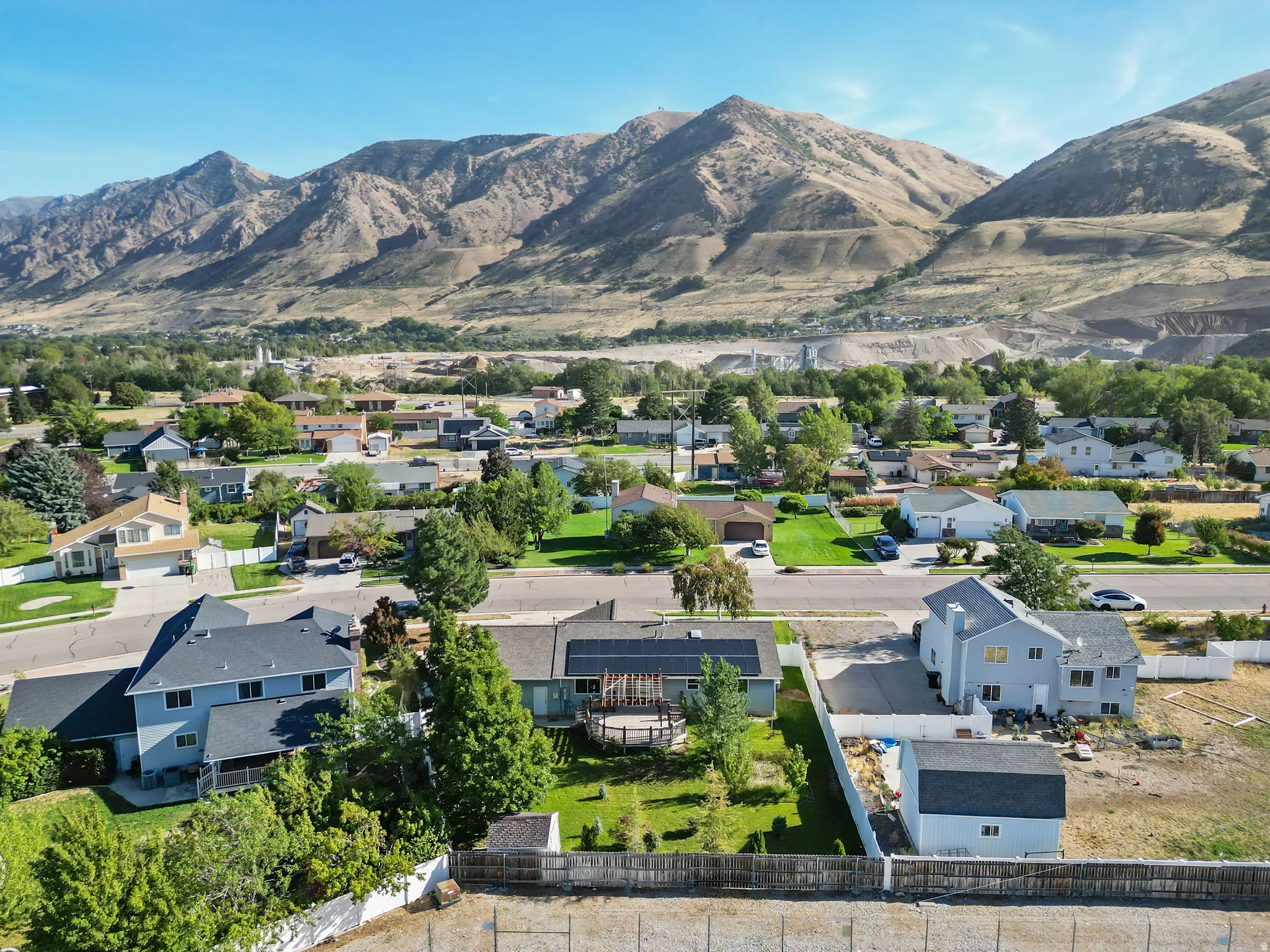 Residential street with diverse housing styles, mature trees, and mountain scenery