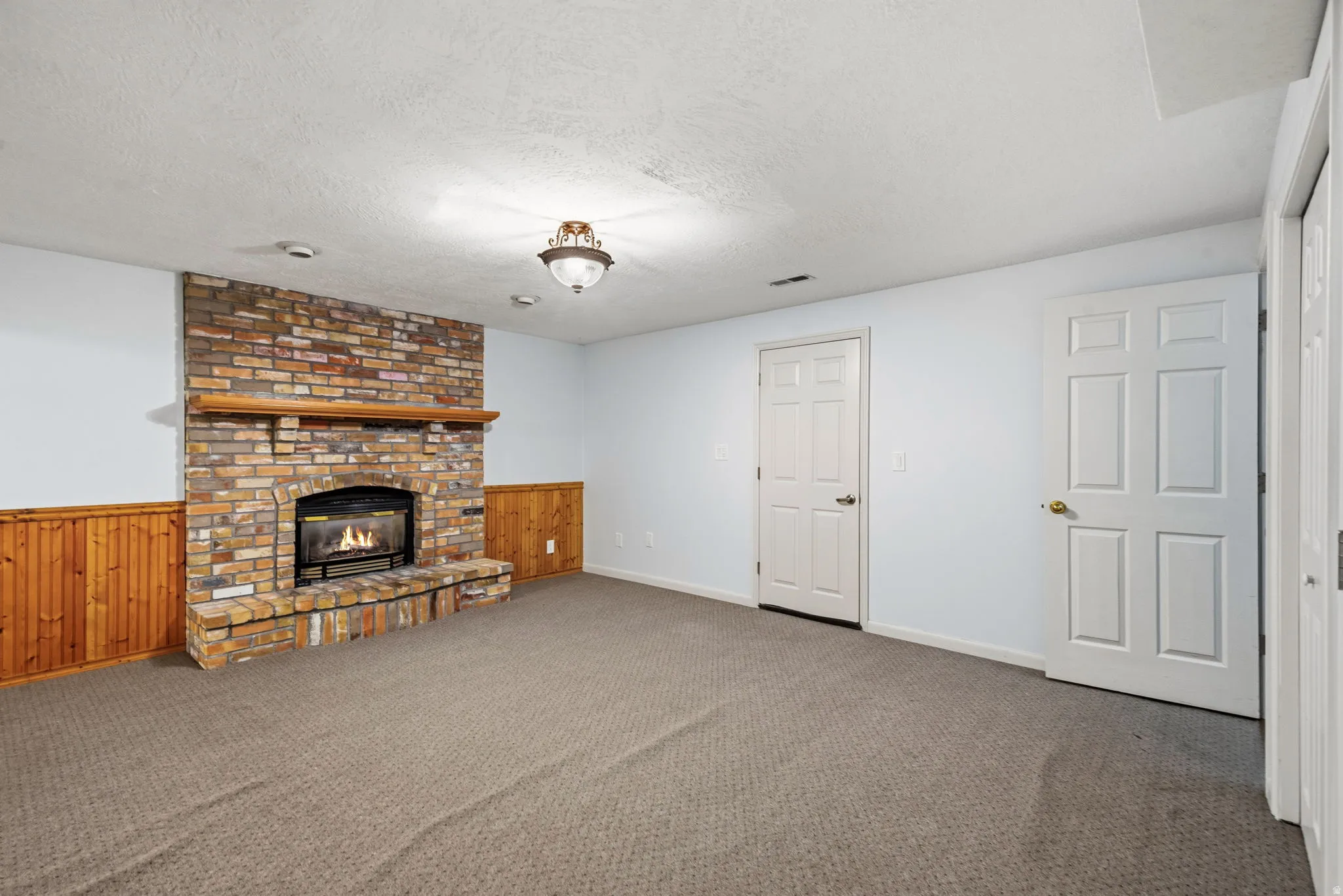Stone-clad fireplace with a wood mantle, complemented by wood paneling and neutral carpeting