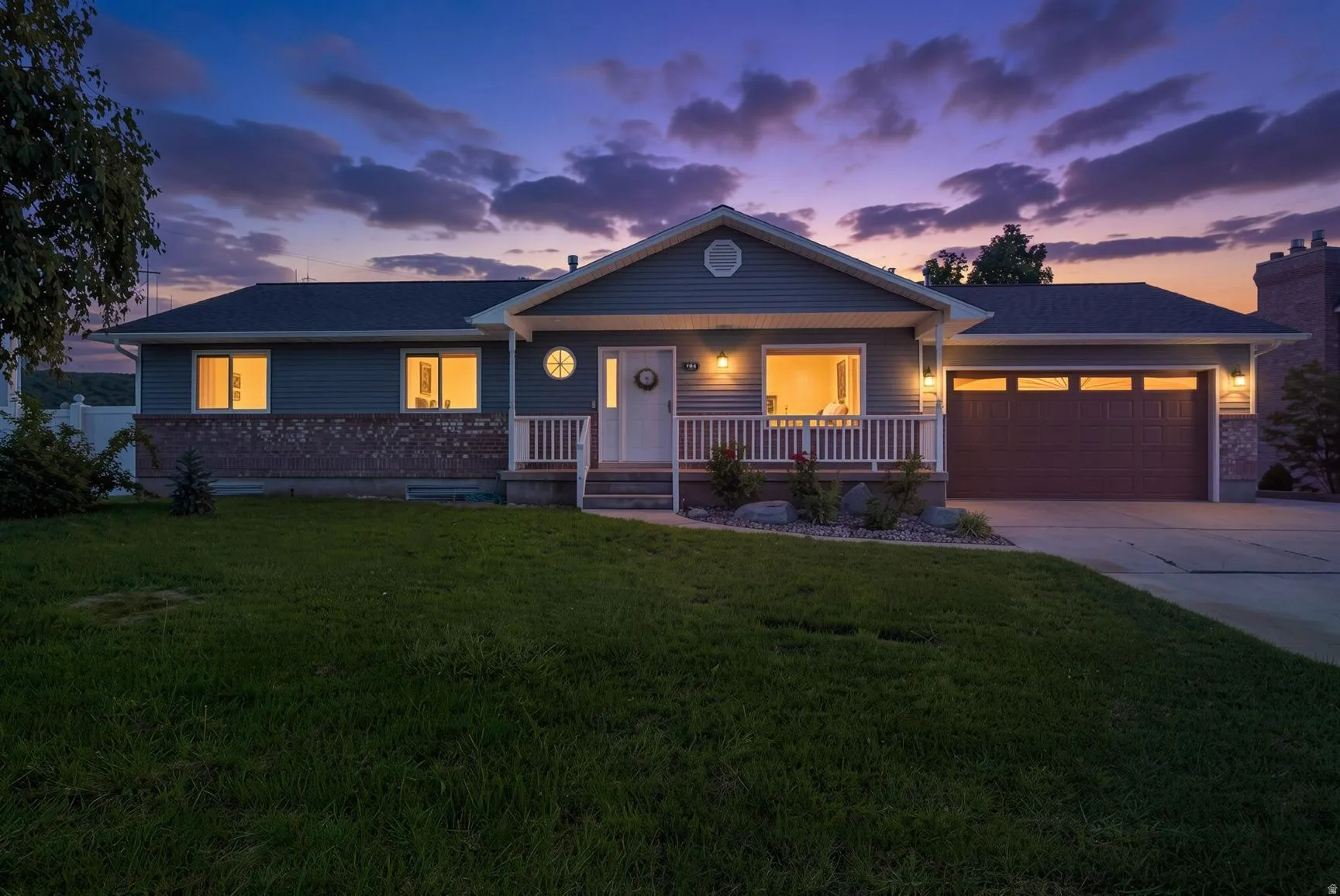 Ranch-style exterior with siding and brick accents, covered front porch, attached garage, and paved driveway