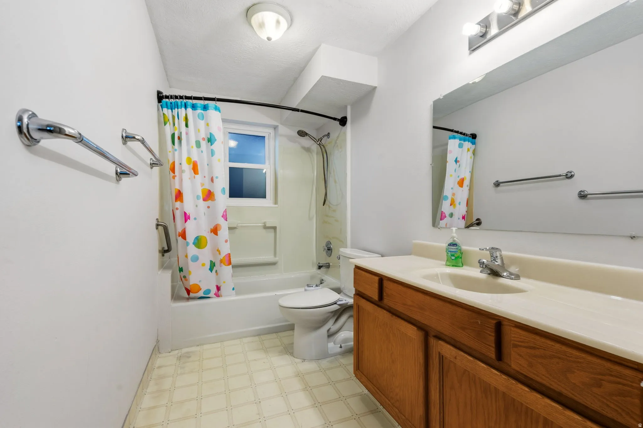 Bathroom featuring a single vanity with wood cabinetry, a built-in sink, and a large mirror