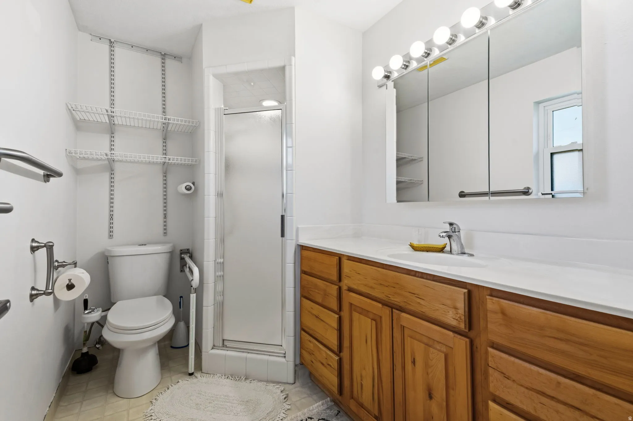 Vanity with wood-finish cabinetry, integrated sink, and white countertop
