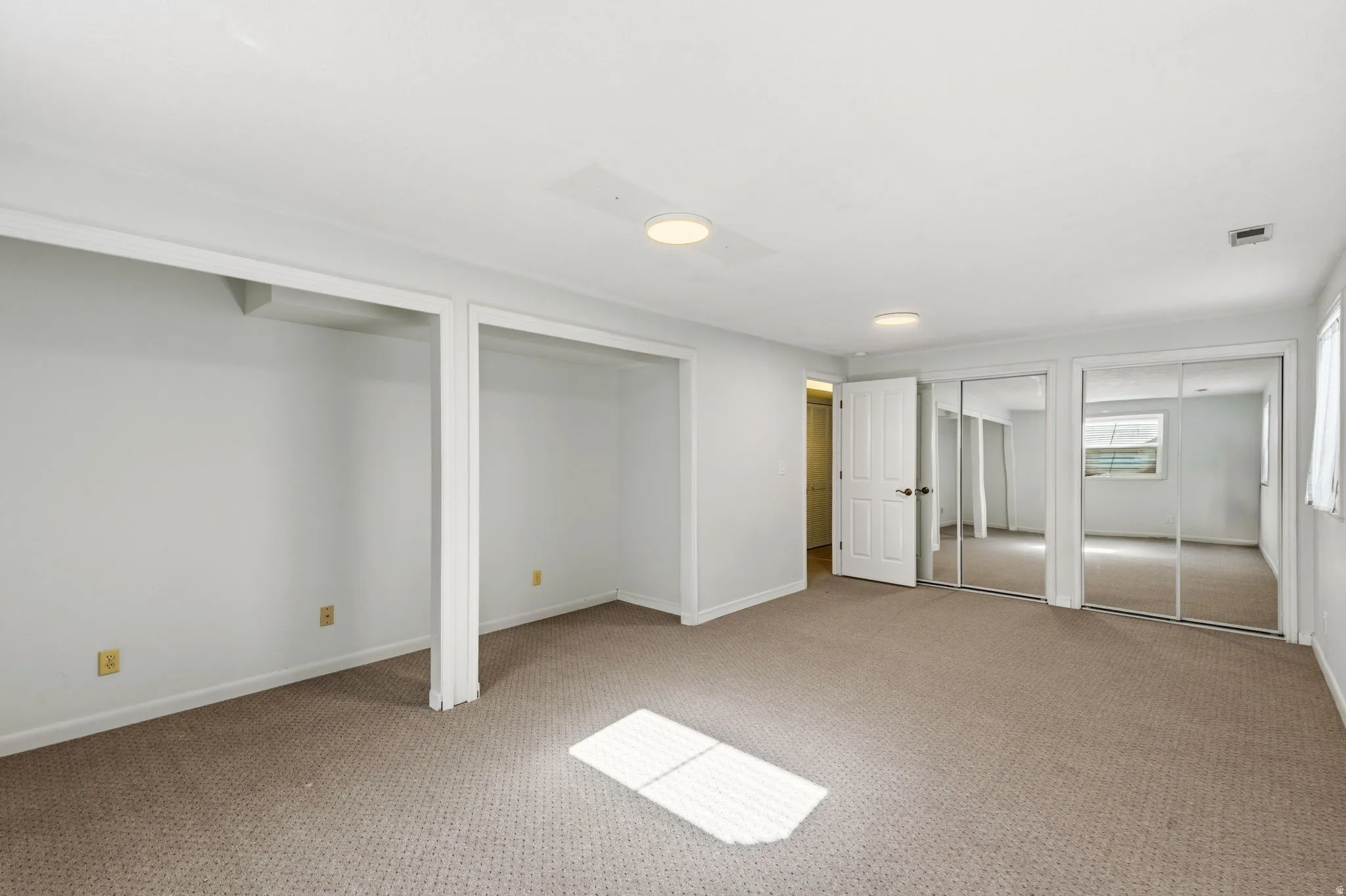 Neutral-toned carpeting, white walls, built-in open shelving, interior white door, and mirrored sliding closet doors