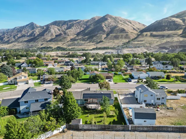 Residential street with diverse housing styles, mature trees, and mountain scenery