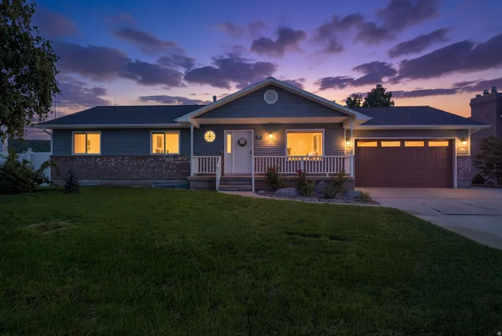 Ranch-style exterior with siding and brick accents, covered front porch, attached garage, and paved driveway