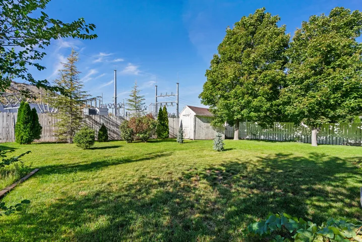 Expansive green lawn with mature trees and a white picket fence