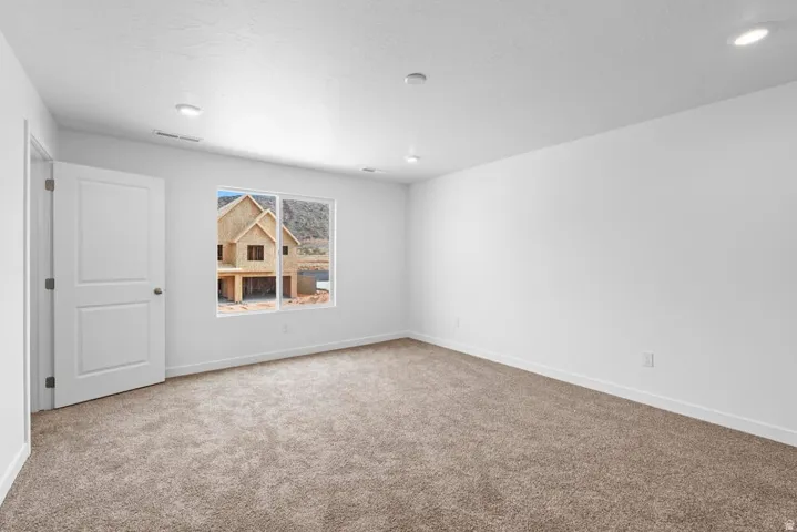 Neutral-toned carpeting, white interior walls, and recessed ceiling lighting
