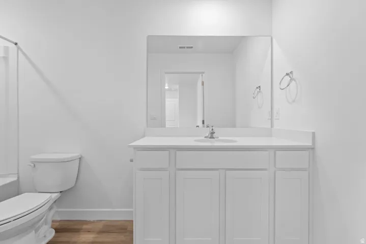 White shaker vanity with a single basin sink, chrome faucet, and expansive wall mirror