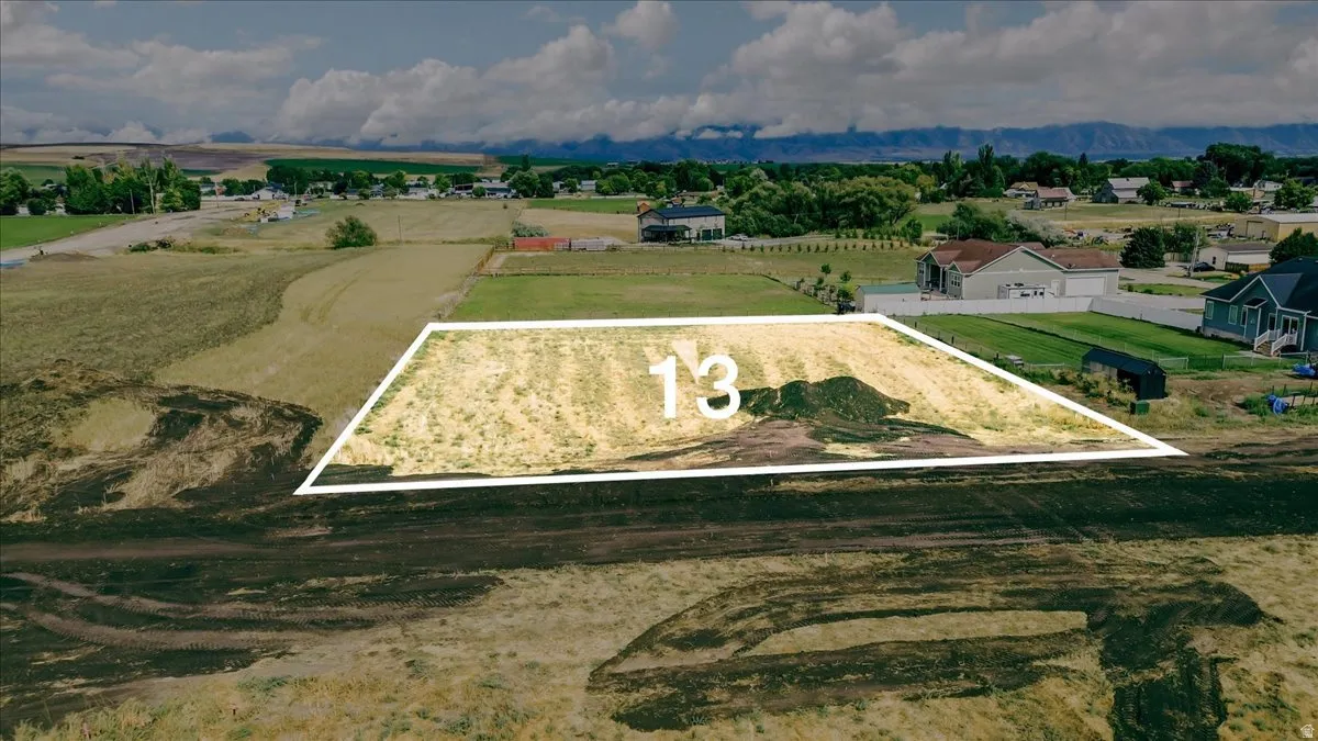 Expansive lot featuring a cleared building site, mountain backdrop, and surrounding residential properties