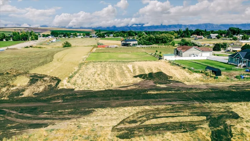 Expansive undeveloped land parcel featuring cleared ground, surrounding agricultural fields, and distant mountain backdrops