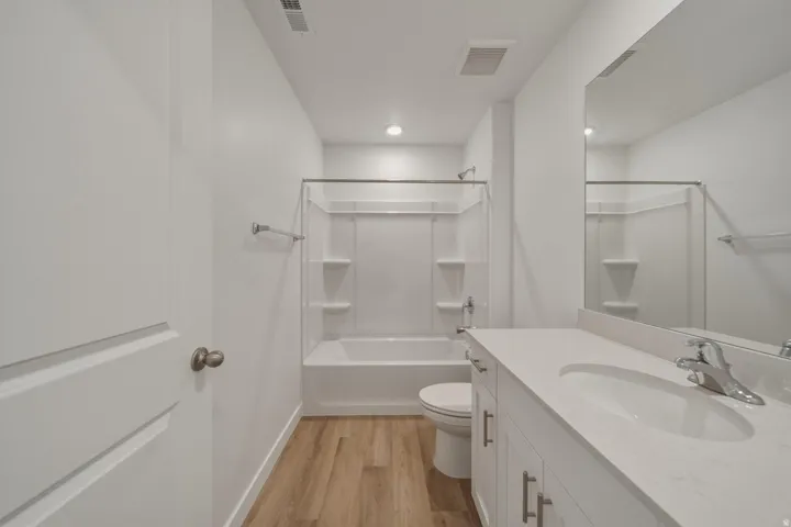 Full bathroom featuring a single vanity with stone countertop, undermount sink, and chrome faucet
