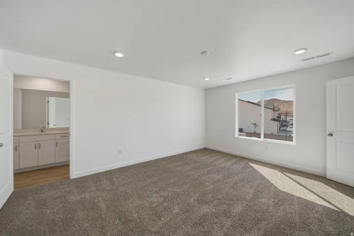 Recessed lighting, light-toned walls, and a large window provide abundant illumination
