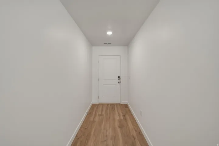 Recessed lighting illuminates wood-finish flooring with crisp white walls