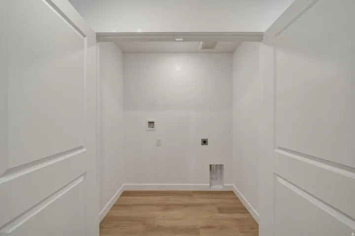 Dedicated laundry area featuring wood-finish flooring, white walls, and panel doors