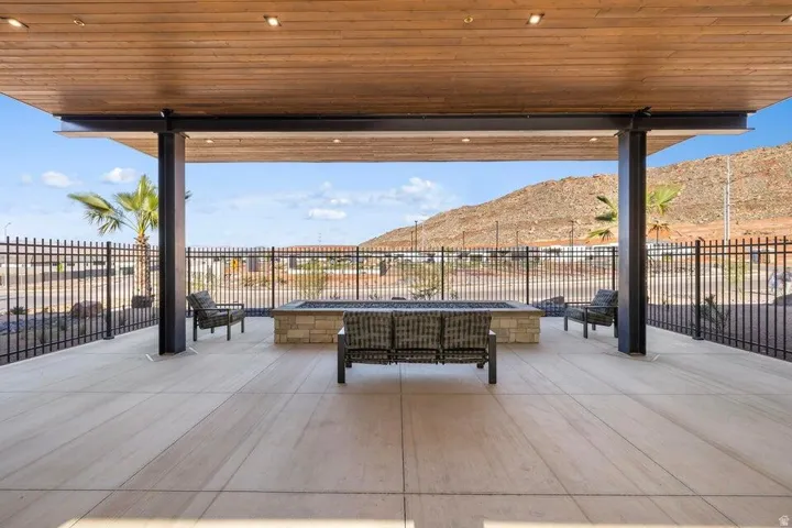 Covered patio featuring a wood-panel ceiling with recessed lighting, a built-in stone fire pit, and durable hardscaping