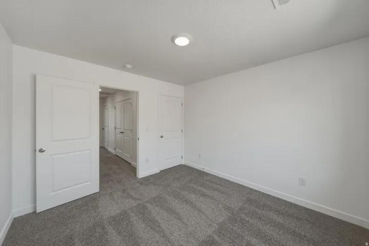 Recessed lighting, light gray carpeting, crisp white walls, white trim, and white paneled doors