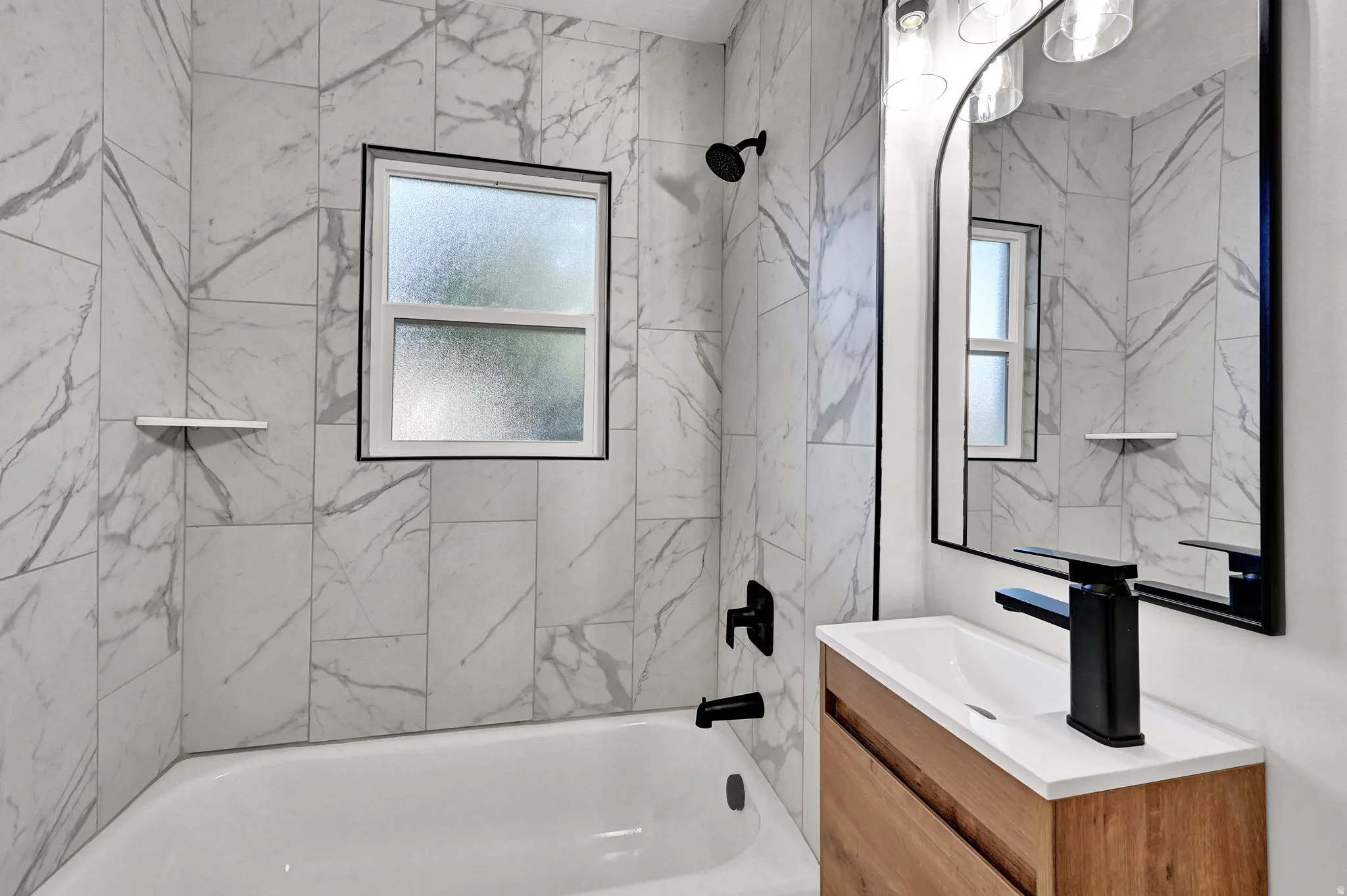 Bathtub with a black-framed window, white marble-style wall tiling, and matte black fixtures