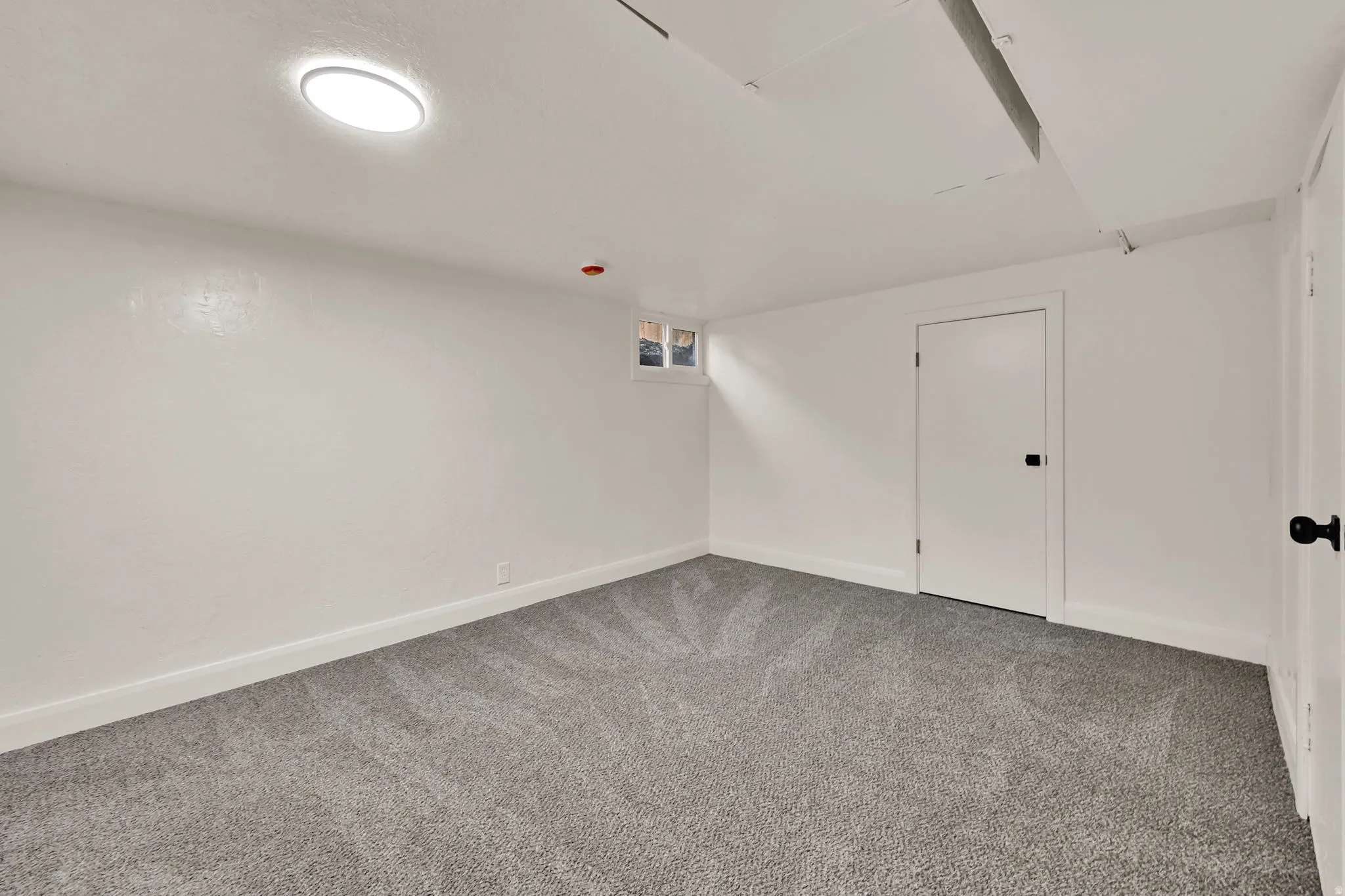 Recessed ceiling light, white painted walls, gray patterned carpeting, white trim, and white doors with dark hardware
