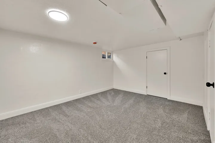 Recessed ceiling light, white painted walls, gray patterned carpeting, white trim, and white doors with dark hardware