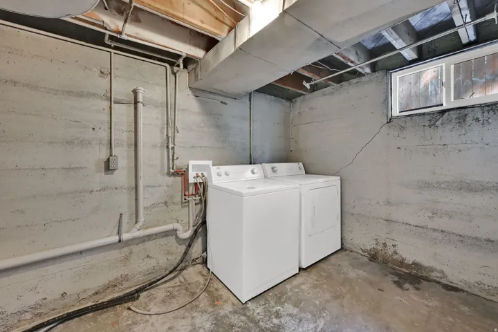Utility space with exposed concrete walls, exposed wood ceiling joists, and a window