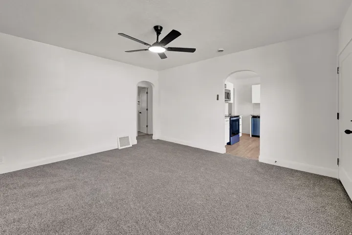 Gray carpeting, white painted walls, and a black ceiling fan with integrated lighting