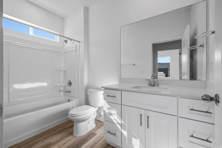 White vanity with a single basin sink, chrome faucet, and expansive wall-mounted mirror