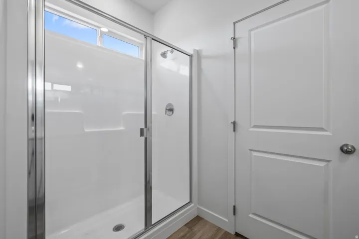 Enclosed shower with a chrome-framed glass door, white shower surround, and a clerestory window