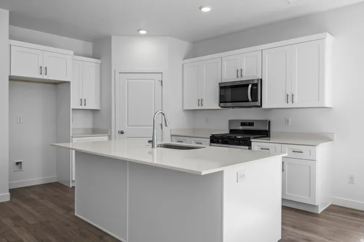 Modern kitchen featuring white shaker cabinetry, light-toned countertops, and wood-finish flooring