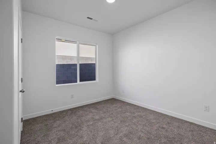 Neutral tone wall finishes, gray textured carpeting, white trim, and a double-paned window