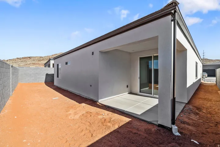 Expansive private backyard with a covered patio, concrete block fencing, and a sliding glass door