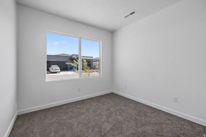 Wall-to-wall carpeting in a neutral tone, white walls, and a large window with white framing
