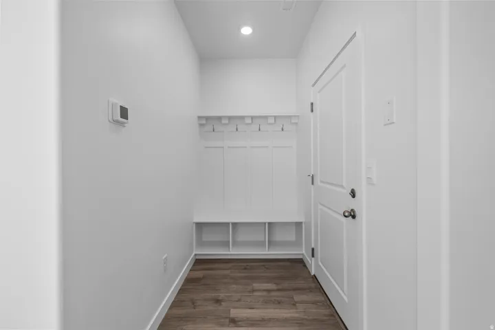 Built-in storage bench with cubbies, shaker-style door, recessed lighting, and wood-finish flooring