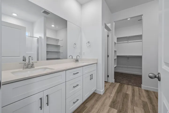 Bathroom featuring a dual vanity with white cabinetry, light-toned countertops, and chrome fixtures