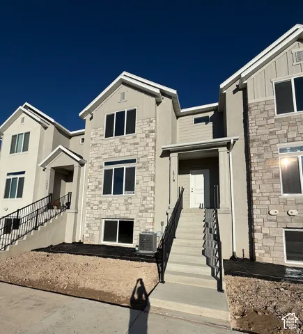 Exterior featuring stone and siding finishes, multiple windows, a covered entry, and black metal railings