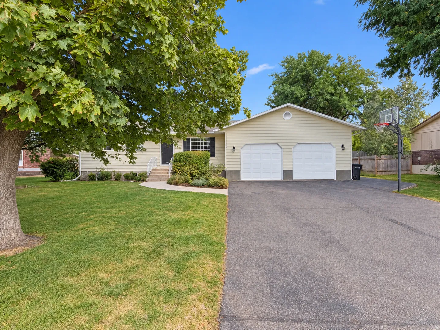 Exterior featuring light-colored siding, a two-car garage, and a paved driveway
