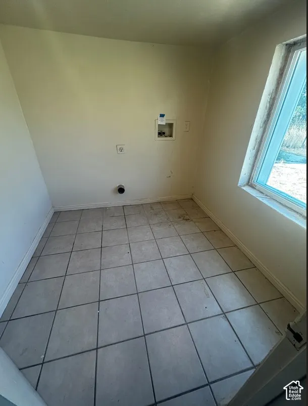 Utility room featuring a tile floor, exterior window, and appliance hookups