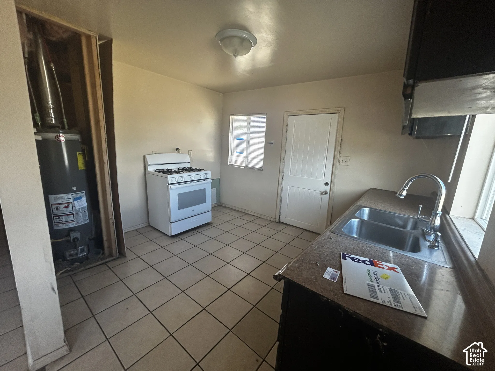 Kitchen with tiled flooring, a stainless steel double-basin sink, and a white freestanding gas range