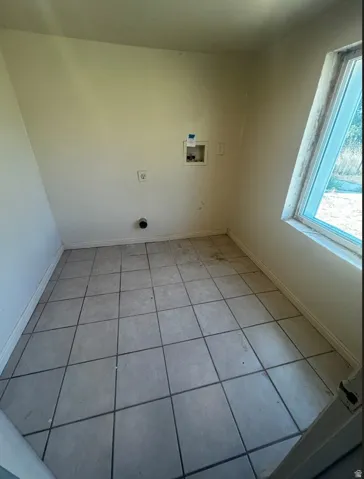 Utility room featuring a tile floor, exterior window, and appliance hookups