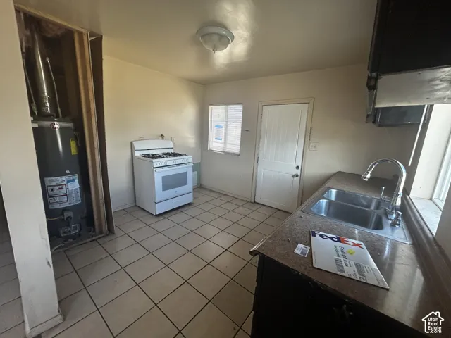 Kitchen with tiled flooring, a stainless steel double-basin sink, and a white freestanding gas range