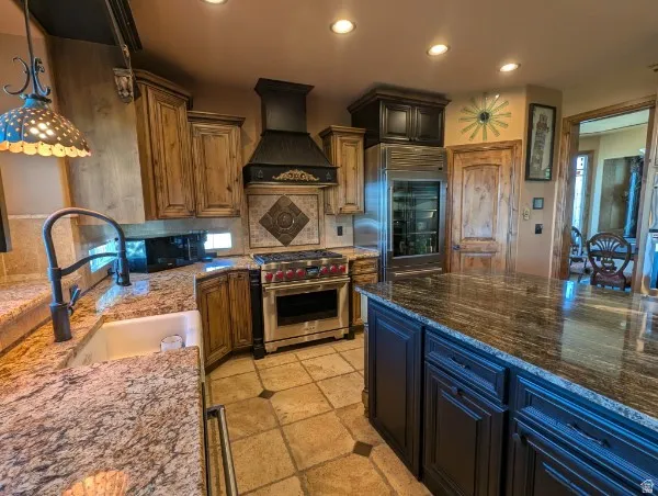 Kitchen featuring granite countertops, wood cabinetry, a built-in range, tiled flooring, and a built-in wine refrigerator