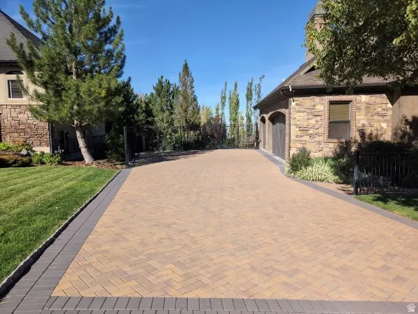 Paver driveway with a herringbone pattern, bordered by a dark gray paver edge