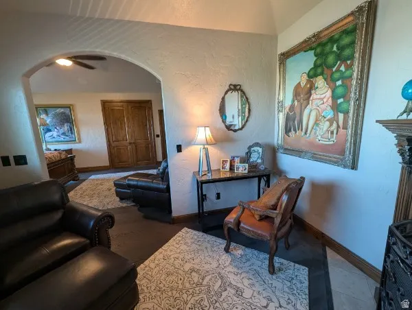 Primary bedroom and sitting room with archway entry with a ceiling fan, dark wood-finish flooring, and light-toned walls