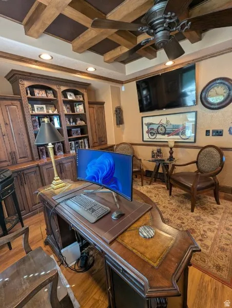 Coffered ceiling with exposed wood beams, ceiling fan with light fixture, built-in wood cabinetry with shelving, wood-finish flooring, and recessed lighting