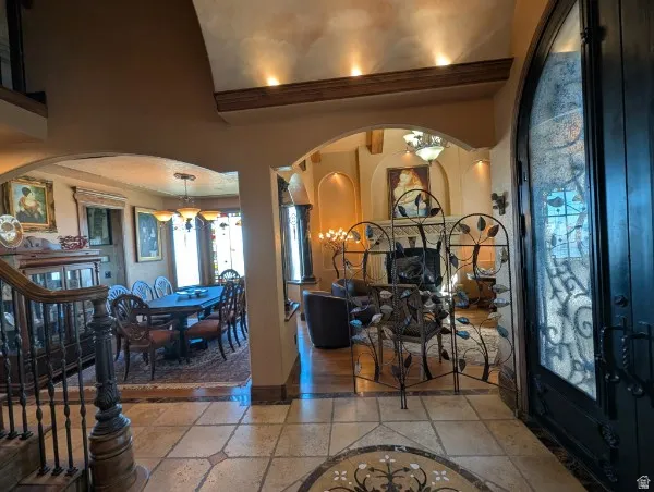 Arched doorways with decorative wrought iron, tile flooring with mosaic inlay, wood-finish flooring, and a decorative fireplace screen